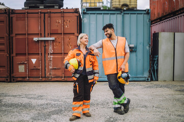 Full length of happy male and female colleagues looking at each other at construction site