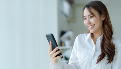 Happy young asian business woman wearing suit holding mobile phone