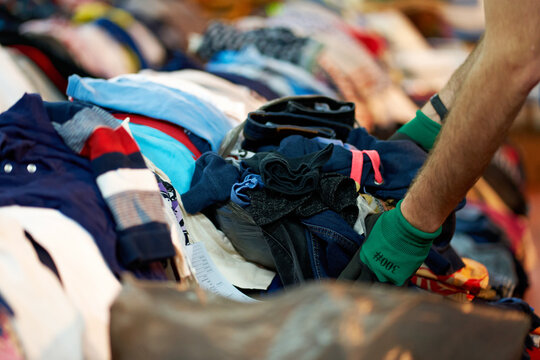 Person sorting second hand clothes by size and gender