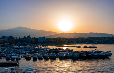 Fototapeta premium picturesque sunrise or sunset in a sea port with a gulf dock pier with tour boats and a town with cloudy sky on background of a seashore landscape