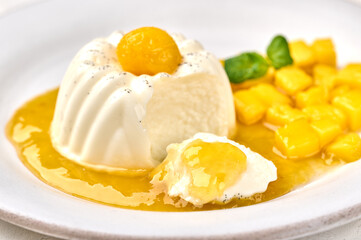 Macro panna cotta homemade and piece with natural vanilla pod, mango syrup and mint, selective focus