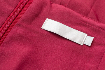 Blank white laundry care clothes label on red fabric texture background