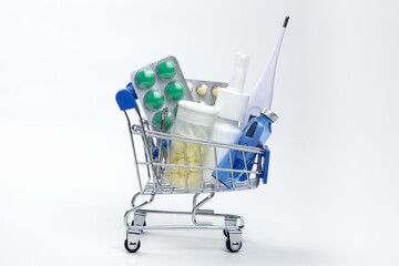 full of medicines little shopping cart on a white background. In trolley there are pills, medicines. Pharmaceutical business concept, online purchase of medicines