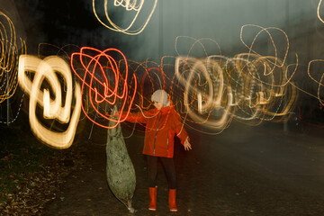 Girl with red jacket playin with a christmas tree in the street with lights