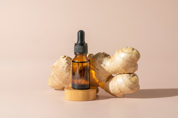 A face or hair serum or essential oil in a brown dropper bottle with a ginger extract standing on a...