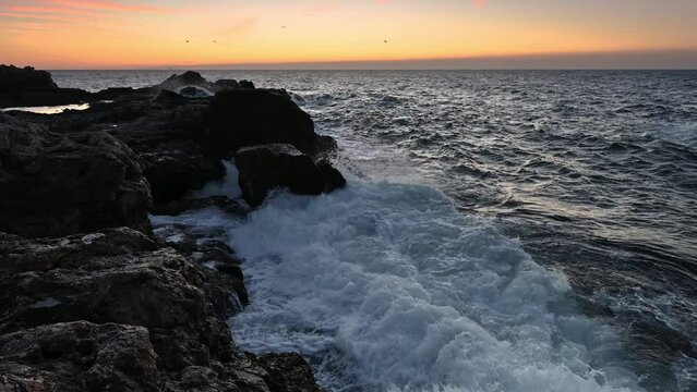 Amazing video with the sun rising, sea waves and a beautiful rocky coast. Slow motion.