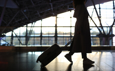 Airport. Beautiful woman with a suitcase at the airport is waiting for her departure. Migration and...