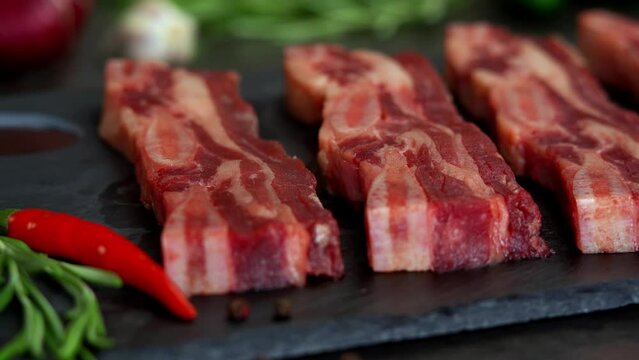 Camera movement on fresh raw beef ribs with seasoning and spices. Pieces of beef steak on bone. Food concept, cooking meat