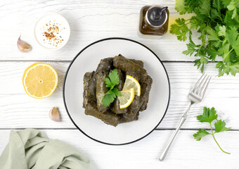 Dolma, matsoni, lemon, parsley on a white wooden background. Traditional Caucasian, Turkish, Armenian and Greek cuisine