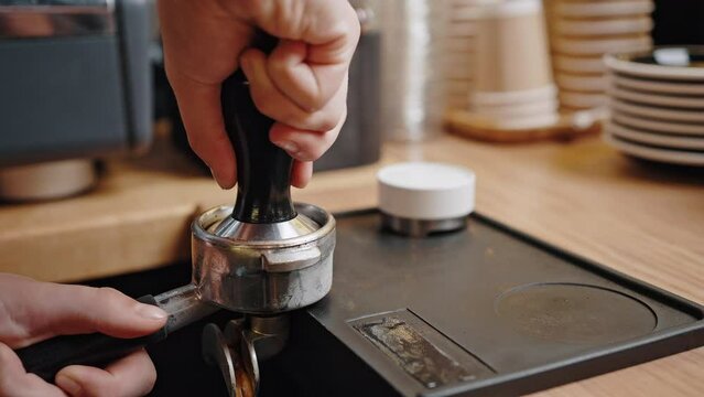Professional barista prepares coffee using portafilter
