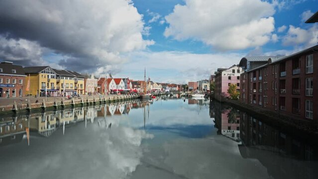 Panoramic View of Husum Harbor in Germany.  Clouds movement time lapse reflected in still water - zoom out motion