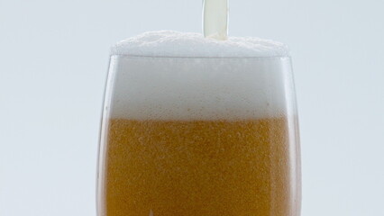 Froth beer pouring bubbling inside glass in super slow motion close up.