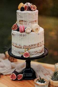 Vertical Shot Of A Beautiful White Cake With Figs On Black Cake Stand