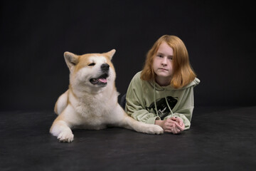 Redhead girl teenager 11-12 years old and dog Akita Inu, child in casual clothes and a purebred dog. Portrait,