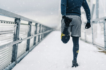 Handsome middle age man with a beard running and exercising outside on extremely cold and snowy...