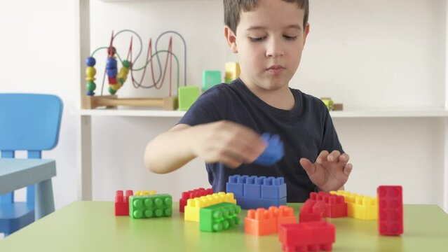 4k video footage of a little boy playing with colourful educational toy blocks on the table at preschool or kindergarten. Kid having fun while engaged in creative learning and development
