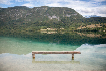 Naklejka na ściany i meble A bench in the clear water of Lake Bohinj, in Slovene: