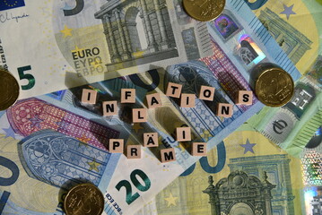Das Wort Inflationsprämie mit Holzbuchstaben auf Euroscheinen