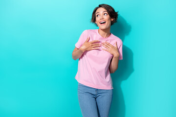 Fototapeta premium Portrait photo of young attractive cute funny lady touch hands chest looking empty space surprised lovely isolated on cyan color background