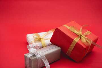 Three gift boxes, red, gray and white. Close up on a red background.