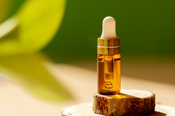 Cosmetic amber glass dropper bottle on wooden podium with oil, serum or fruit peeling in the...