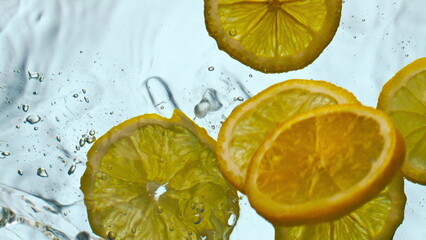 Fototapeta na wymiar Sliced sour lemon falling water making splashes in super slow motion close up.