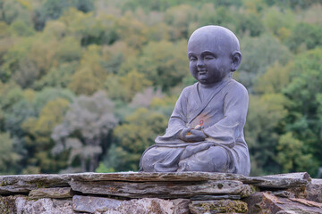 Child Buddha sculpture on stone wall. Triacastela, Lugo, Galicia, Spain. French Way of Saint James.