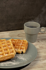 Plate with freshly baked waffles with a cup of hot black coffee - concept breakfast, snack, pastries