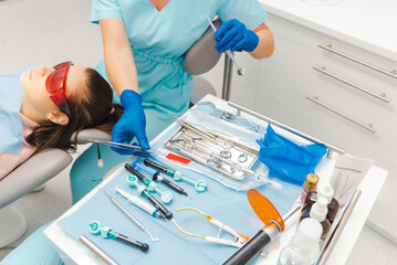 Working process of a dentist for a woman near some dentistry instruments.