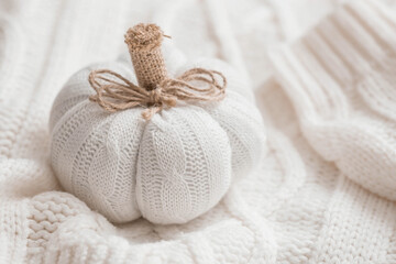 White knitted pumpkin, autumn leaves and a white knitted plaid. Stylish, warm, cozy autumn concept.