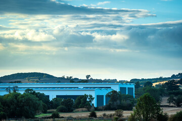 Obraz premium new built distribution warehouse building with farm fields in foreground in england uk