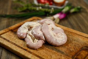 Cow bowels presented on a wooden board with ingredients, ready to grill