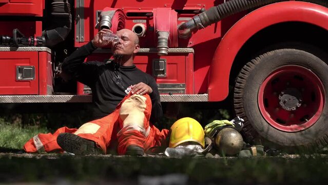 Portrait of a firefighter wearing a firefighting suit with equipment. water truck background	