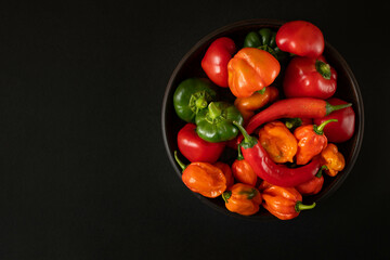 Peppers in a bowl. Peppers of different varieties on a dark background.