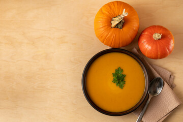 Pumpkin soup in a bowl on a wooden table.