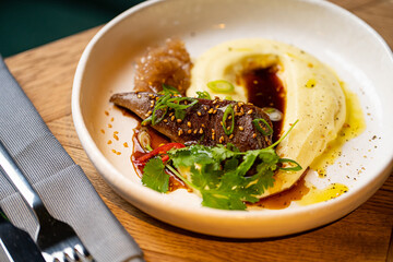 mashed potatoes with grilled meat on a white plate in a restaurant