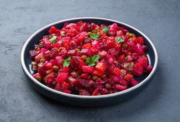 Traditional salad vinaigrette with beetroot, vegetables and peas on a dark background. Side view, close-up