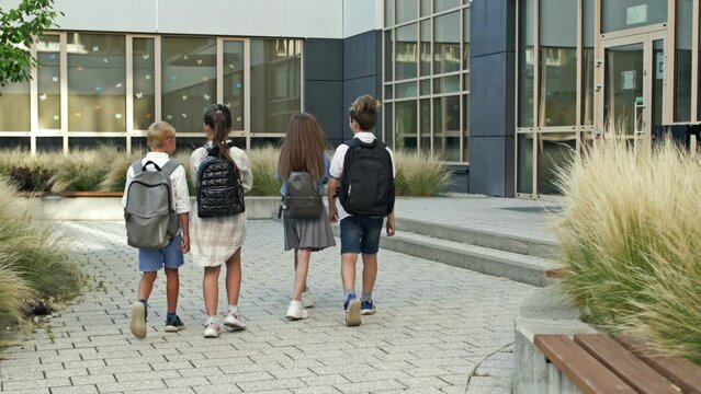Children of primary school age go to school. Backpacks behind.