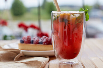 Refreshing raspberry-mint orange lemonade with cane straw outside. Raspberry tart