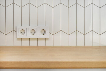 View of kitchen wood countertop and white chevron tiles. Built-in socket. Minimalistic Scandinavian design. Free empty space work surface and hob.surface.