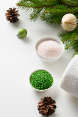 Obraz na płótnie Canvas Winter body skin care and Christmas Spa concept and preparation before holiday. Cosmetic sea salt , baubles, evergreen fir branches on white background. Special offer for beauty services. Copy space