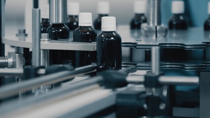 Fototapeta na wymiar Automated production line conveyor in a factory with screw caps on glass bottles. Medical Conveyor Production of Pharmaceuticals. Twist Bottles. Pharmaceutical Industry. Close up, DOF