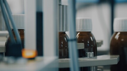 Automated production line conveyor in a factory with screw caps on glass bottles. Medical Conveyor Production of Pharmaceuticals. Twist Bottles. Pharmaceutical Industry. Close up, DOF