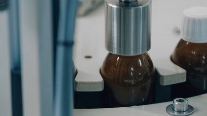 Automated production line conveyor in a factory with screw caps on glass bottles. Medical Conveyor Production of Pharmaceuticals. Twist Bottles. Pharmaceutical Industry. Close up, DOF