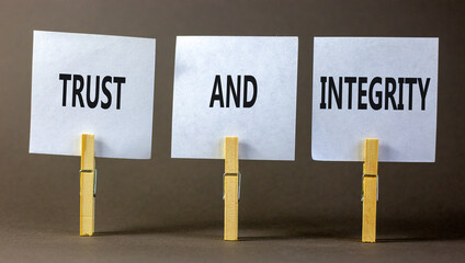 Trust and integrity symbol. Concept words Trust and integrity on white papers on wooden clothespins. Beautiful grey table grey background. Business and trust and integrity concept. Copy space.
