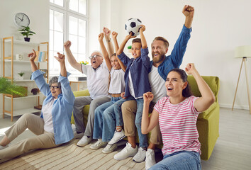 Super excited and happy big multi-generational family watching football match together. Grandparents, preteen boy and girl and their parents cheer emotionally watching World Cup soccer match on TV.