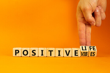 Positive vibes and life symbol. Concept words Positive vibes or Positive life on wooden cubes. Businessman hand. Beautiful orange background. Business positive vibes life concept. Copy space