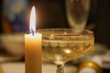 Christmas still life. A glass of champagne sparkling wine with bubbles and a candle. High quality photo