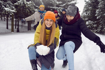 Funny cheerful couple of female and male friends having fun outdoors with snow in winter forest....