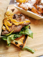 Delicious sandwitch with cooked slices of pork steak onions and vegetables. Fastfood snack